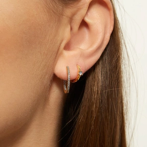 Elegant gold hoop earrings set with sparkling cubic zirconia and blue stones on model