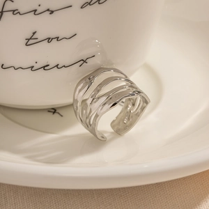Minimalist multi-layer wavy silver steel open ring displayed on a white ceramic cup