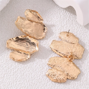 Macro detail of gold irregular geometric earrings with vintage hammered metal texture