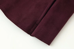 Detailed close-up of dark red suede jacket with high-quality stitching and texture