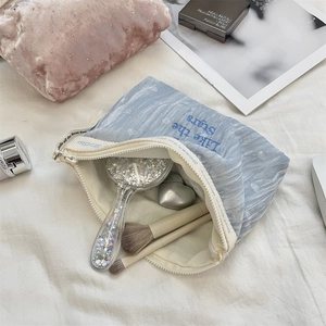 Detailed view of light blue velvet cosmetic bag with embroidery and smooth zipper