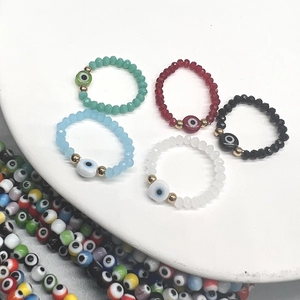 Colorful beaded Evil Eye stretch rings set with gold accents on a white display base