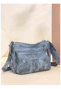 Detail view of washed blue vintage crossbody bag with multiple zipper compartments