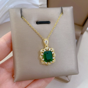 Vue macro d'un collier doré avec pierre verte émeraude et zircons étincelants