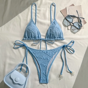 Detail of light blue bikini featuring textured fabric and elegant white pearl accents