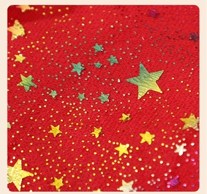 Macro shot of red plush fabric with golden star sequins and texture on the Christmas hat