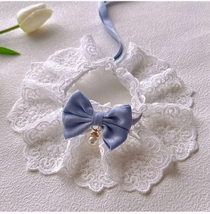 Close-up of white lace pet collar with a blue satin bow and elegant pearl pendant