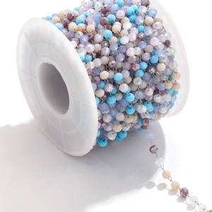 Detailed close-up of colorful faceted crystal beads on a stainless steel chain on a spool