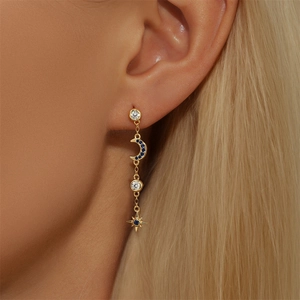 Detail showing elegant gold star and moon tassel earrings with blue crystals on model