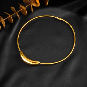 Minimalist gold curved pendant on wire collar displayed on black silk with eucalyptus leaf