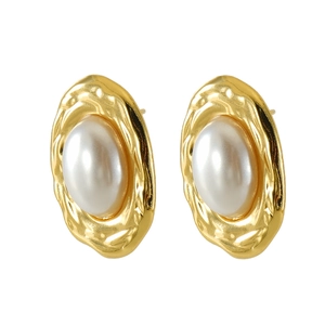 Detailed macro view of vintage hammered gold earrings with elegant white faux pearl inlay