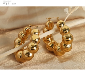 Detailed view of gold beaded U-shaped earrings on smooth fabric background