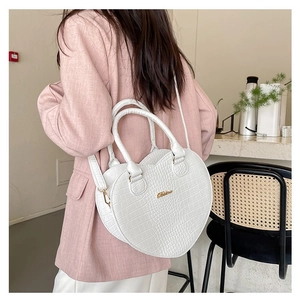 Détail du sac à main blanc en forme de cœur avec motif crocodile et accents dorés
