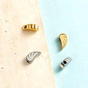 Detailed view of gold and silver feather-shaped steel charms with textured wing design
