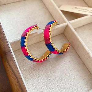 Detail of colorful knitted C-shaped hoop earrings with gold metal studs and texture