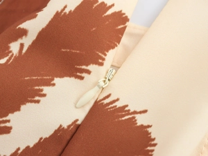 Detail of invisible zipper closure on brown and beige printed fabric dress
