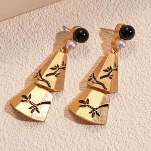 Detail of vintage gold earrings with imitation pearls and black floral fan pendants