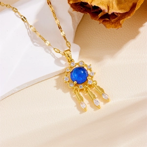 Golden dreamcatcher necklace with blue gemstone and feathers on beige stone background