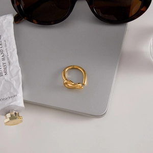 Minimalist 18K gold knot heart open ring on laptop with stylish lifestyle accessories