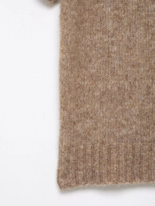 Close-up of brown knit vest showing soft fiber texture and ribbed hem detail