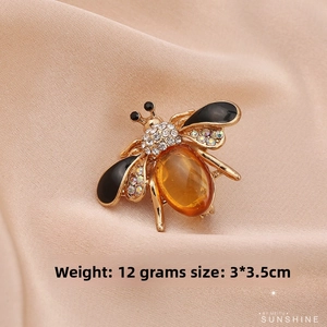 Detailed view of bee brooch with amber gemstone, white crystals, and black enamel wings