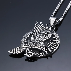 Close-up of a Viking crow totem pendant with Nordic runes on a black reflective surface