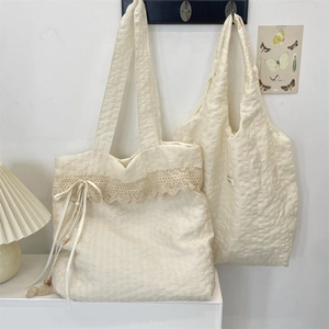 Close-up of cream canvas tote bag with delicate lace trim and ribbon bow detail