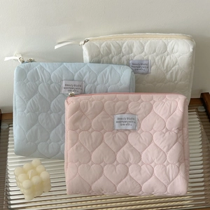 Detailed view of soft quilted heart cosmetic bags in cream, blue and pink pastel tones