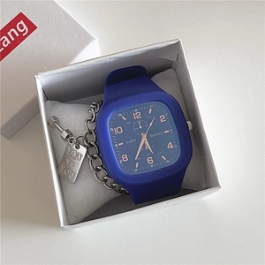 Close-up of blue square quartz watch with silicone strap and metal tag in gift box
