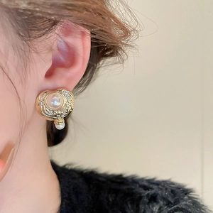 Dettaglio di orecchini vintage in metallo dorato con perle finte e piccoli diamanti