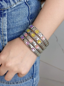 Close-up of stacked stainless steel elastic bracelets with colorful oval gemstones