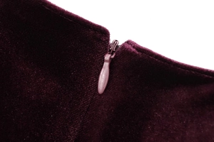 Nahaufnahme des verdeckten Reißverschlusses am eleganten tiefvioletten Samtkleid