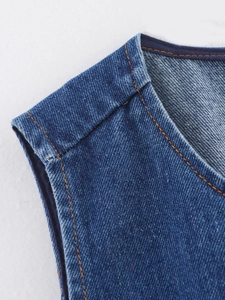 Détail rapproché du gilet en jean bleu foncé avec coutures orange contrastées