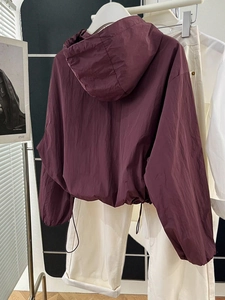 Detail of burgundy windbreaker jacket showing adjustable drawstring hem and zipper closure