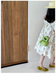 Detail of green cloud-shaped crossbody bag with pearl handle and golden chain strap