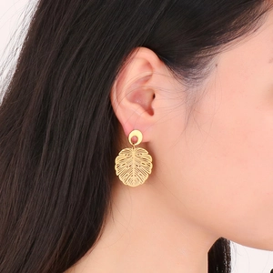 Detail view of 18K gold-plated monstera leaf earring worn on a model's ear