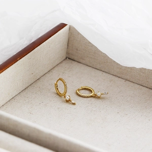 Close-up of gold hoop earrings with small pearls and diamonds in a luxury jewelry box