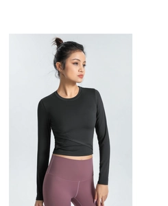 Détail du haut de yoga noir à manches longues avec taille croisée et legging violet taille haute