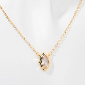 Detailed view of a gold diamond-shaped pendant necklace with a clear zircon stone