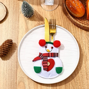 Close-up of snowman silverware holder on a white plate with festive Christmas decor