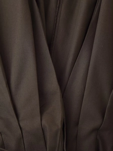 Close-up of pleated dark brown cotton fabric showing high-quality stitching and texture