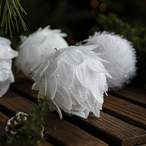White pine cone Christmas balls with glitter finish on festive pine tree branches