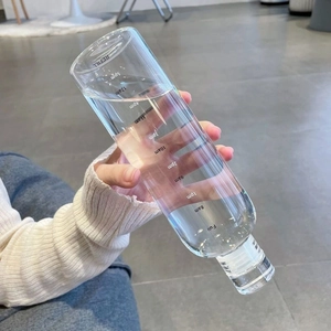 Close-up of minimalist clear plastic water bottle with time markers held by hand