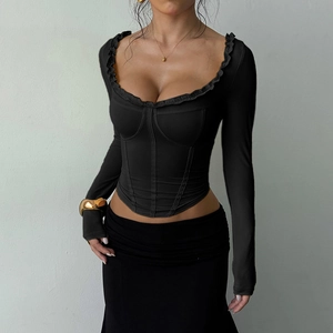 Detailed view of the ruffle neckline and elastic knit fabric on a black long-sleeve top