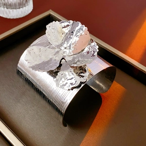 Detail of silver flower cuff bracelet with brushed metal texture and hammered finish