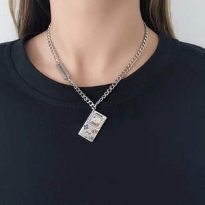 Detail of silver game console pendant necklace with branded tag on black t-shirt
