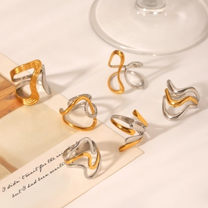 Detailed view of wavy bicolor gold and silver stainless steel rings on a minimalist desk