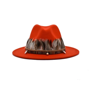Detail of red fedora hat featuring real feathers, ethnic woven band and metal pendant