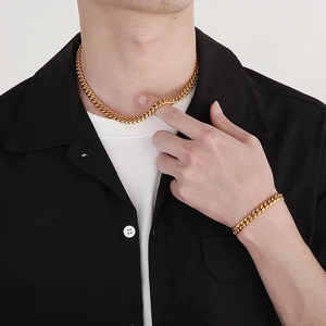 Close-up of a man wearing a matte and polished gold Cuban link necklace and bracelet set