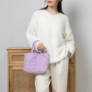 Detail of lavender quilted heart pattern handbag with soft padded nylon texture